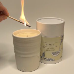 candle in a hand thrown pot being lit with a match